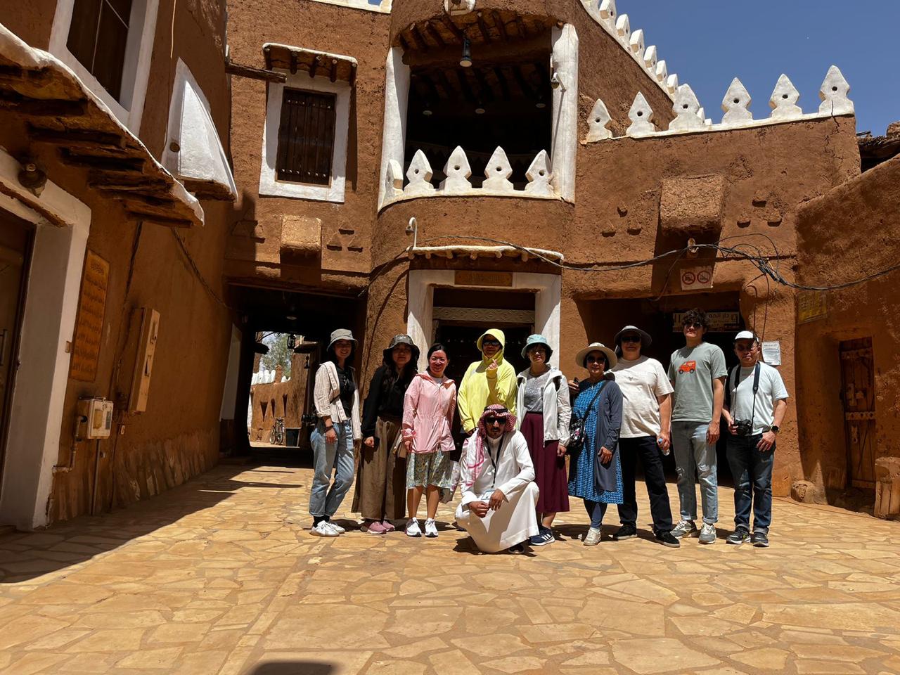 Visitors outside a traditional mud-brick building in Saudi Arabia