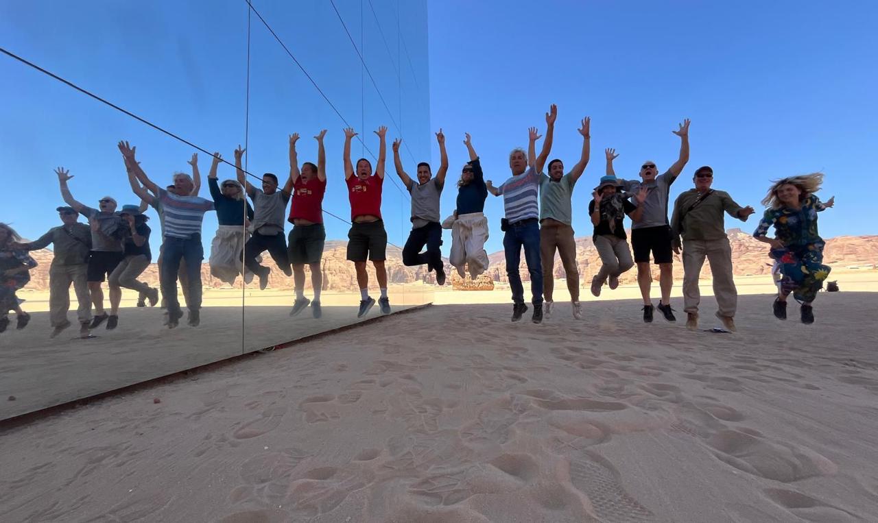 Visitors jumping beside a mirrored building in the Saudi desert